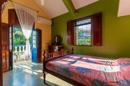 Lov Heritage Goa في Chinchinim: غرفة نوم بسرير مع جدران خضراء ونوافذ