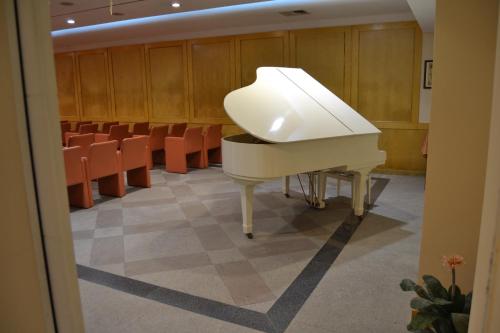 a white piano in a room with chairs at Hotel Excelsior in Lanciano