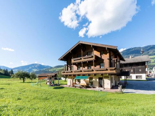 a large wooden house in a field with mountains at Beautiful apartment in Mittersill with balcony in Mittersill