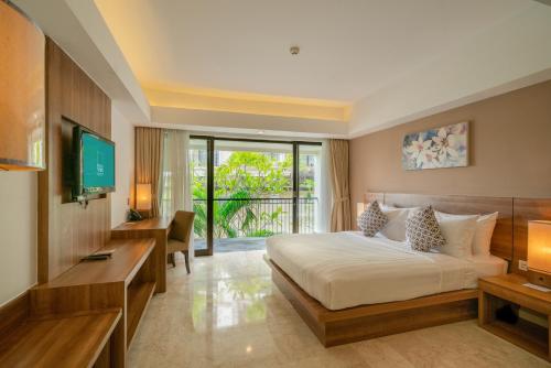 a hotel room with a bed and a television at Cross Vibe Paasha Atelier Bali Kuta in Kuta