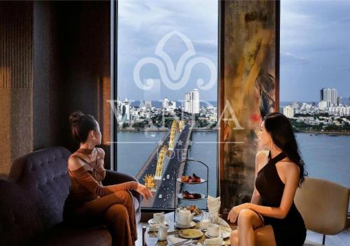 Vanda Hotel في دا نانغ: امرأتان تجلسان في مطعم وتنظران من النافذة