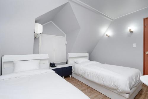 two beds in a room with white walls at Chuncheon Stay in Chuncheon
