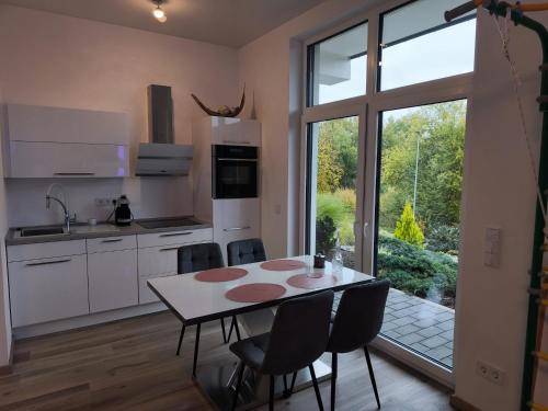 een keuken met een tafel en stoelen en een groot raam bij Modernes Apartment in ruhiger Lage inklusive Fitnessgeräte für Ihr Workout zu Hause in Drolshagen