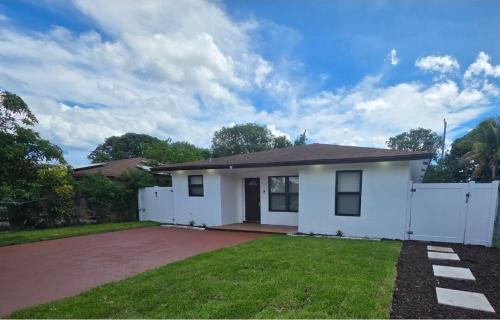 a small white house with a white fence at Delray Beach Sunshine - 5 minutes from beach! in Delray Beach