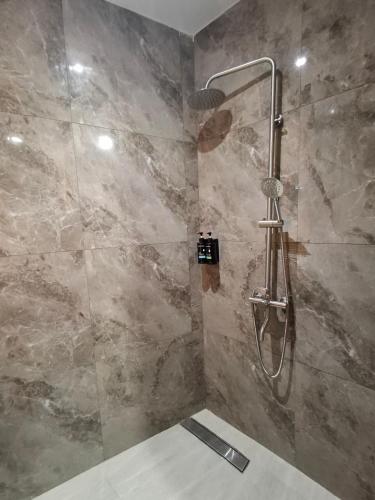 a shower in a bathroom with a stone wall at The Castle Medan Penginapan Syariah in Medan