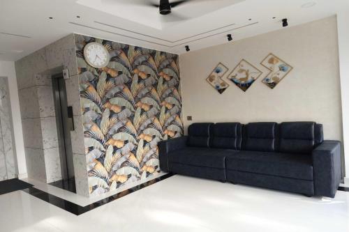 a living room with a couch and a clock on a wall at Townhouse Cochin Airport Formerly Skyluxe in Nedumbassery