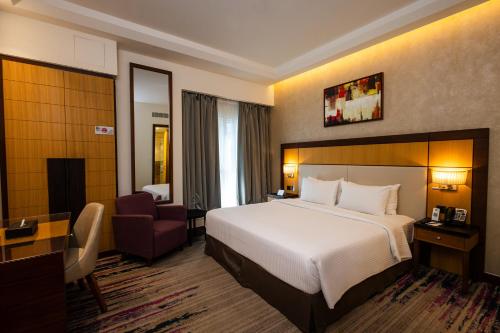 a hotel room with a bed and a chair at Golden Tulip Media Hotel in Dubai