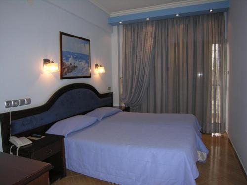 a bedroom with a large white bed and a window at Filippos in Nea Moudania