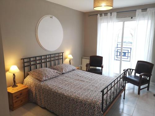 Un dormitorio con una cama y dos sillas y un espejo. en Superbe Appartement 2 Chambres, en La Ciotat