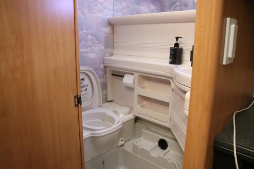 a small bathroom with a toilet and a sink at Full Service Caravan 3 in Søborg