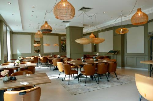 een restaurant met tafels en stoelen en hanglampen bij Hotel Amadeus Frankfurt in Frankfurt am Main
