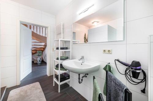 a white bathroom with a sink and a staircase at Großes Ferienhaus Im Grünen - in Beselin