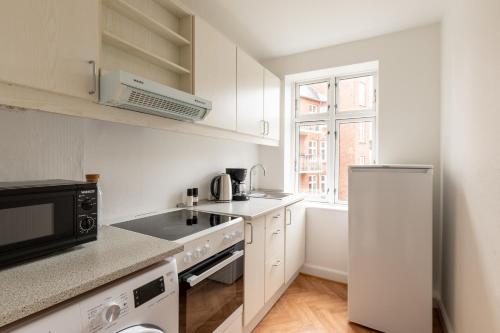 a white kitchen with a sink and a refrigerator at Homely 5 Person Apartment in Amager in Copenhagen
