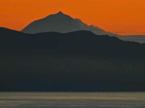 a mountain in the distance with a sunset behind it at Stunning ocean view with 3 islands in front of you in Serreta