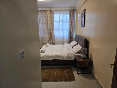 a small bedroom with a bed and a window at Pofu Stay Eldoret in Eldoret