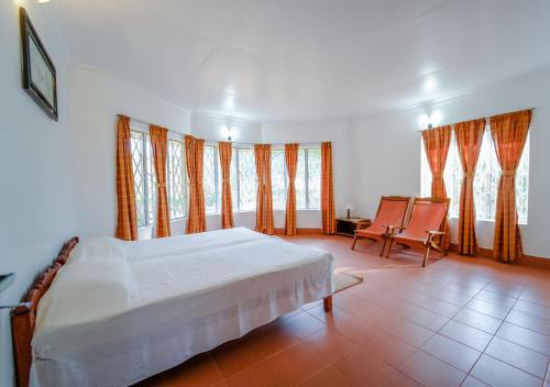 Un dormitorio con una cama y una mesa y sillas. en Viriparai Tea Bungalow by VOYE HOMES, en Munnar