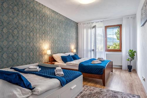 een slaapkamer met twee bedden en een raam bij Apartmán KaTry in Veľká Lomnica