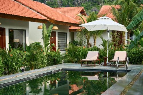 a villa with a pool and two chairs and an umbrella at The Greenary Garden in Ninh Binh