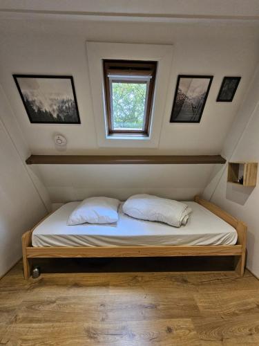 a bed with two pillows in a room with a window at De Berghut Durbuy - Chalet nr 104 in Durbuy