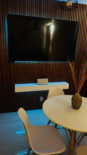 a table with two chairs and a tv on a wall at Departamento moderno a un lado de la feria in Pachuca de Soto