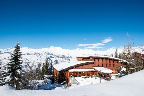a building in the snow with mountains in the background at Villages Clubs du Soleil - ARC 1800 in Arc 1800