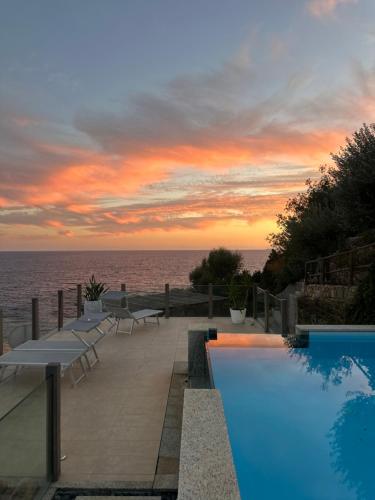 una piscina con vista al mar al atardecer en BeLocations - Villa and Beach On The Rocks, en Torre delle Stelle