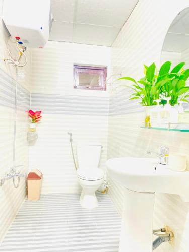 a white bathroom with a toilet and a sink at Dona Hotel in Da Lat