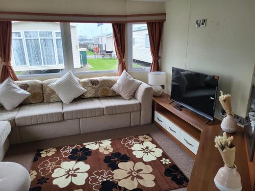 a living room with a couch and a flat screen tv at Caravan by the Sea 640 in Kinmel Bay