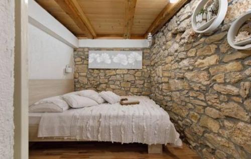 a bed in a room with a stone wall at Holiday home Lisnjak by Villas Guide in Trbounje