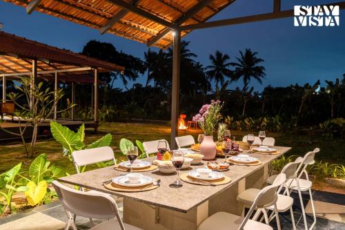 a table set for a meal under a pergola at StayVista at Villa Atharva Anekal Bengaluru in Bengaluru