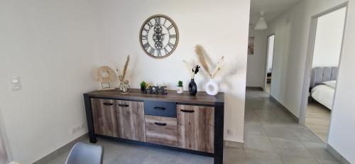 un reloj en una pared sobre un tocador en una habitación en Villa Soléa - Proche Océan, en Grayan-et-lʼHôpital