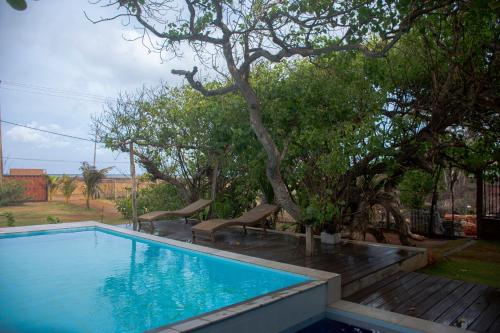 a swimming pool with two chairs and a tree at Sundowners in Chilaw