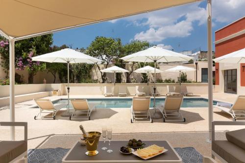 a pool with chairs and tables and umbrellas at Palazzo Fasti in Casarano