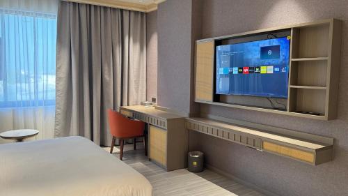 a hotel room with a bed and a flat screen tv at Amaris Hotel in Al Ḩamrāʼ