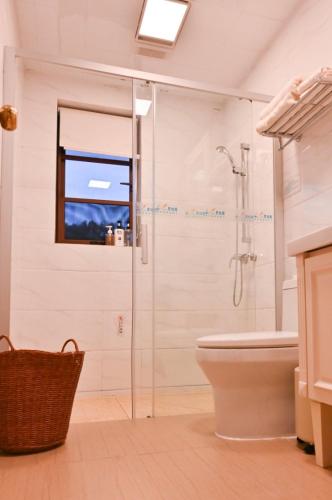 a bathroom with a glass shower and a toilet at Shushushe B&B in Jiawan