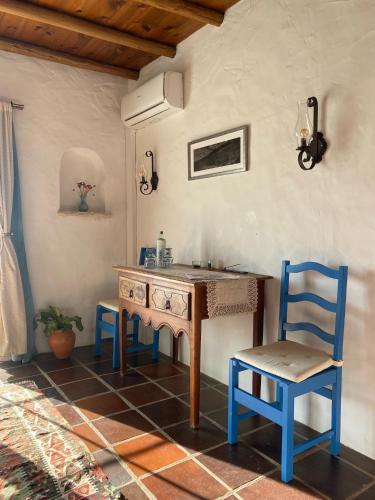 a kitchen with a wooden table and two blue chairs at Quinta Mourada in São Bartolomeu