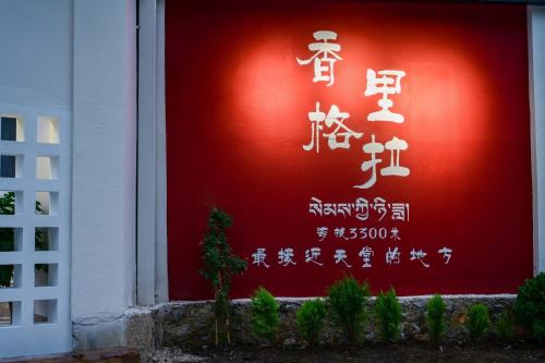 a red wall with chinese writing on it at Da Le Zhi Ye Homestay in Shangri-La