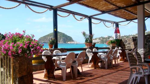 a deck with tables and chairs and a view of the ocean at Hotel La Gondola in Ischia