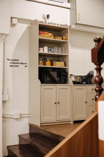 a kitchen with white cabinets and a microwave at Samranscape in Bangkok