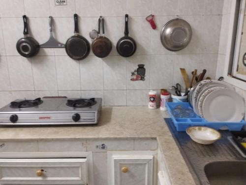 una cucina con piano cottura e pentole e padelle appese al muro di Muscat Women's Hostel a Mascate