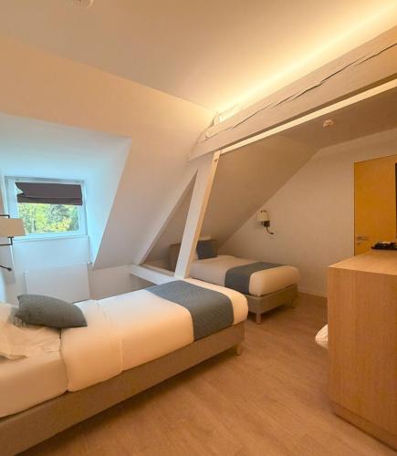 a hotel room with two beds and a window at Maison Des Augustines in Saint-Amand-les-Eaux