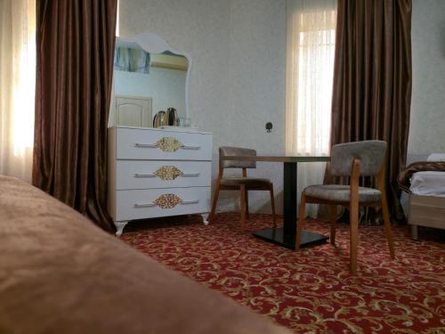 a bedroom with a bed and a desk and a dresser at SaraSofi Hotel in Baku