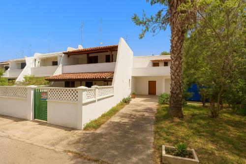 una casa bianca con una palma di fronte di Adriatic Suite - Casa vacanze nel Salento a SantʼAndrea