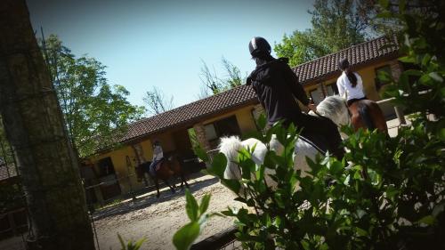 two people riding horses in front of a building at La Cascina Del Castello in Asti