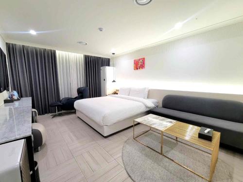 a hotel room with a bed and a couch at Hotel PIED Suseong in Daegu