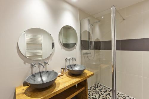 two sinks in a bathroom with two mirrors at Les Logis du Théâtre in Poligny