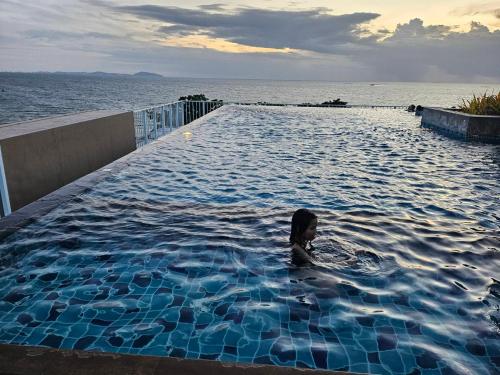a person in a swimming pool next to the ocean at The Blu X See Sea F6 R153 in Ban Bang Saen (1)