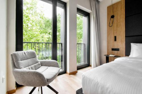 a bedroom with a bed and a chair and a window at HAYASHI Boutique Apartments in Sofia