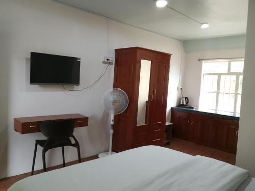 a bedroom with a bed and a desk and a television at Spring Grove B&B in Jowai