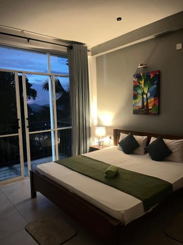 a bedroom with a large bed with a large window at kandy hill villa in Kandy